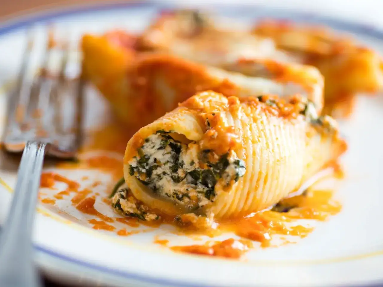 Pyszne conchiglioni faszerowane ricottą i szpinakiem, polane sosem pomidorowym. Idealne do wypróbowania w domowych ricotta przepisach.