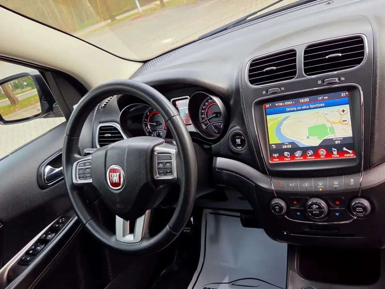 Wnętrze Fiata Freemont. Kierownica z logo Fiat, ekran nawigacji z mapą i panelem sterowania. Dobre fiat freemont opinie to podstawa.