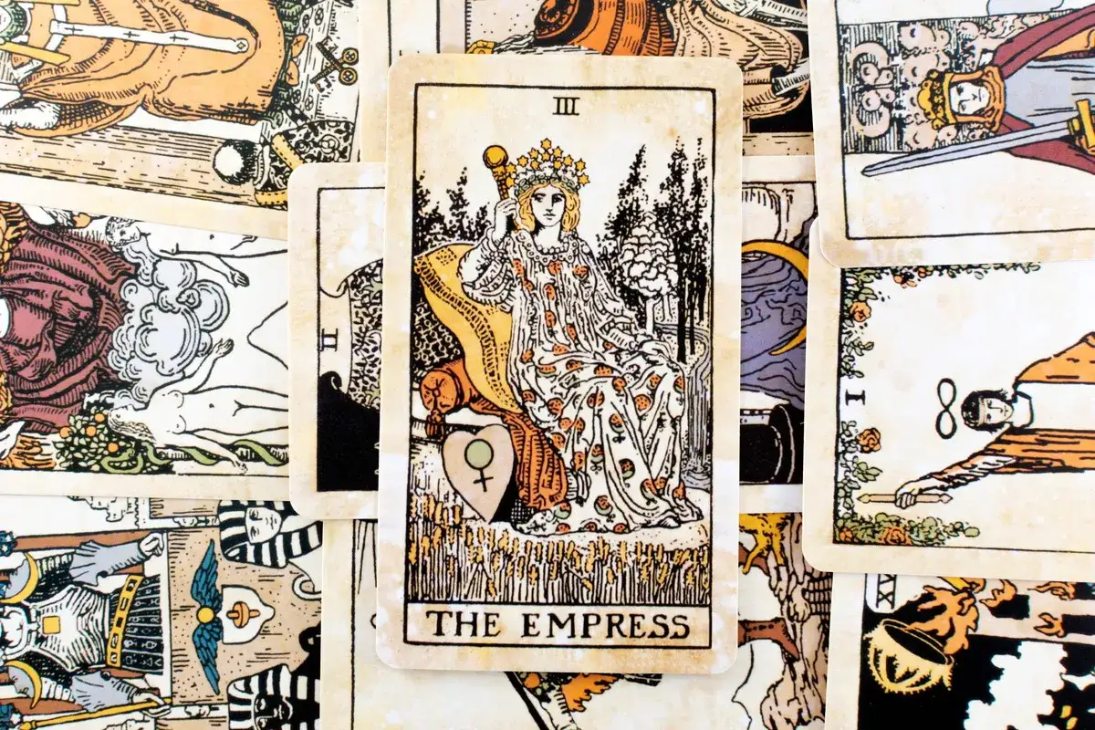 Karta cesarzowa tarot, przedstawiająca kobietę w koronie, siedzącą na tronie, otoczona symbolami płodności i natury.