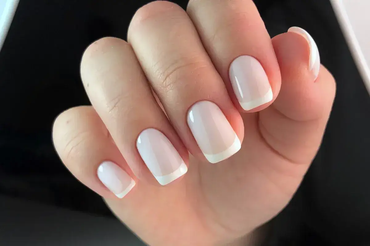 Delikatna stylizacja paznokci w stylu francuskim. Jasny róż i biel tworzą klasyczny, elegancki manicure.