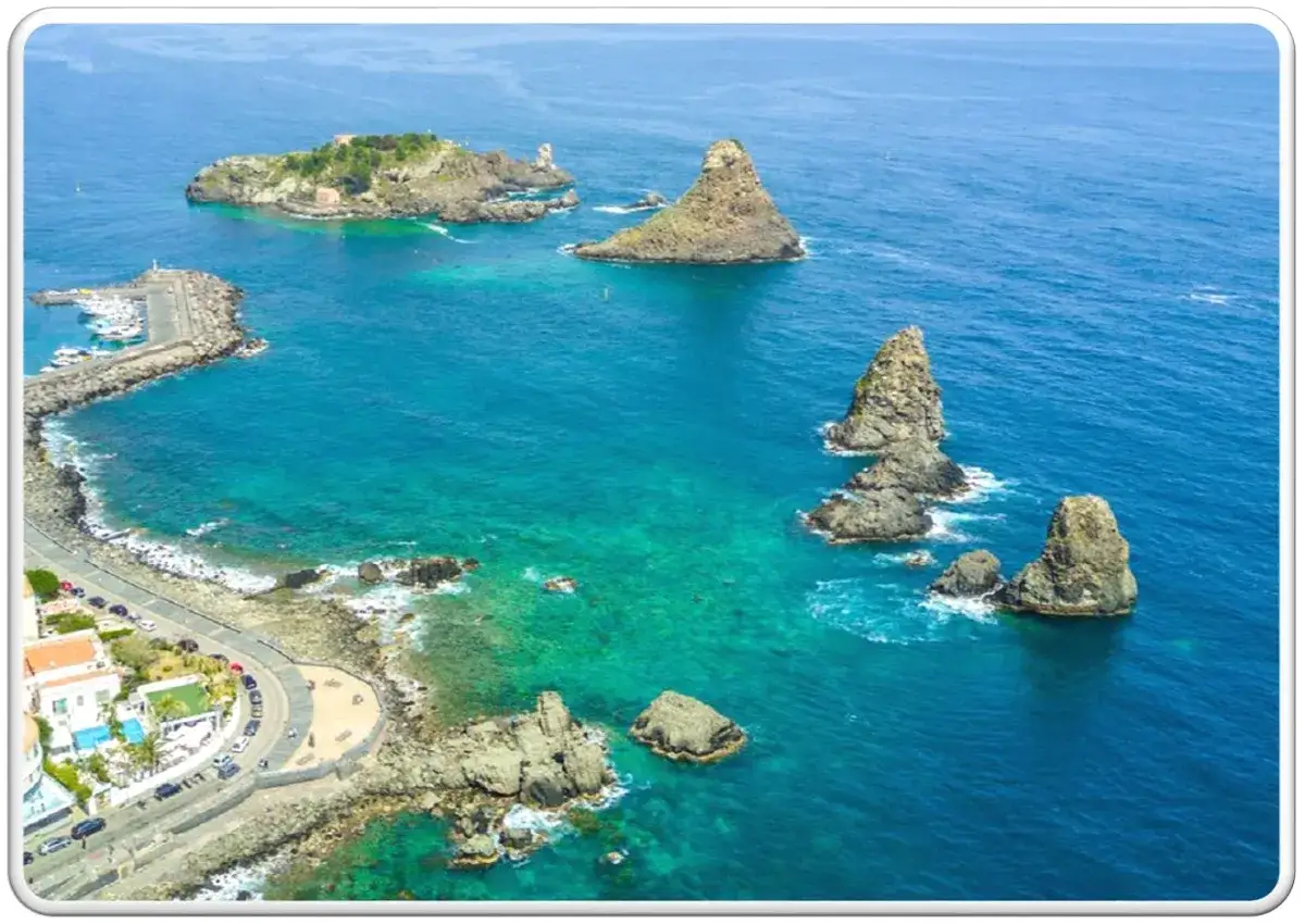 Faraglioni di Acitrezza, uno scenario da romanzi siciliani, con il mare turchese e un piccolo porto.