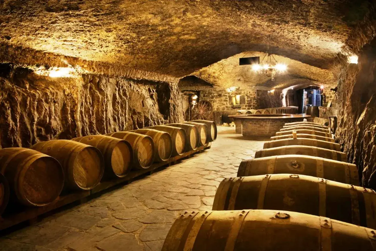 Bodega subterr&aacute;nea con barricas de roble alineadas, evocando la tradici&oacute;n del medoc alav&eacute;s.