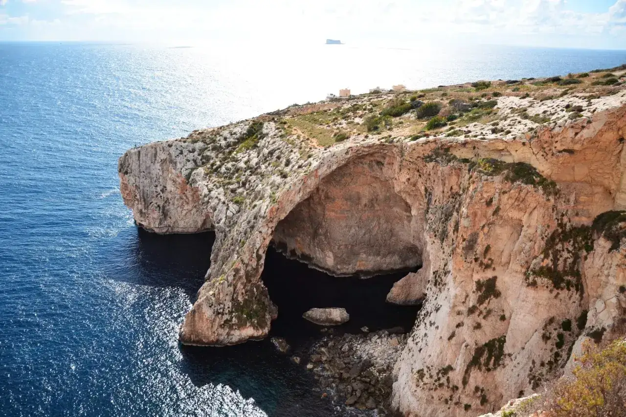 Malta zwiedzanie: imponująca jaskinia w klifie nad turkusowym morzem, idealne miejsce na odkrywanie uroków wyspy.