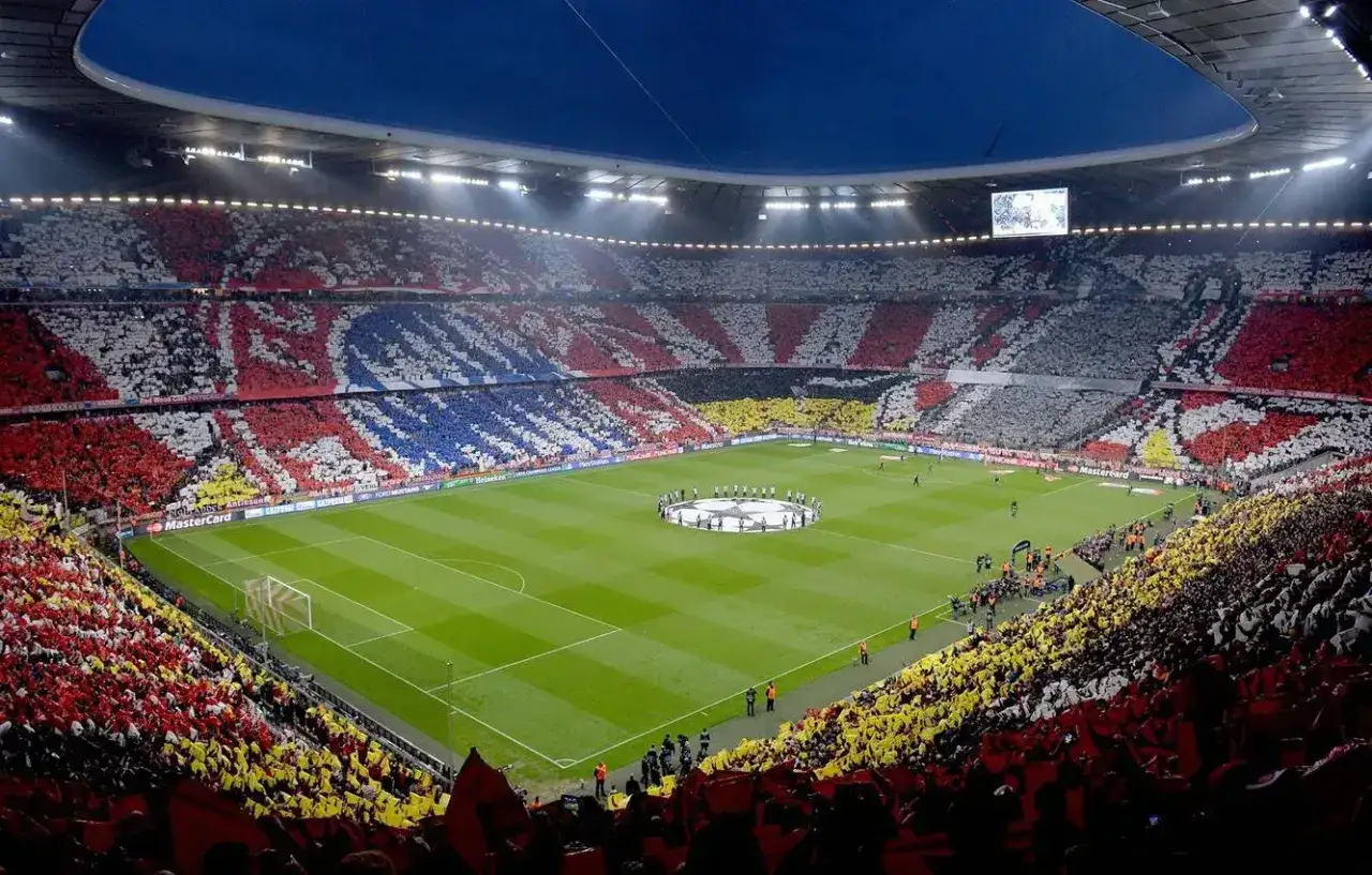 Widok na murawę i trybuny Allianz Arena, gdzie kibice tworzą barwne mozaiki.