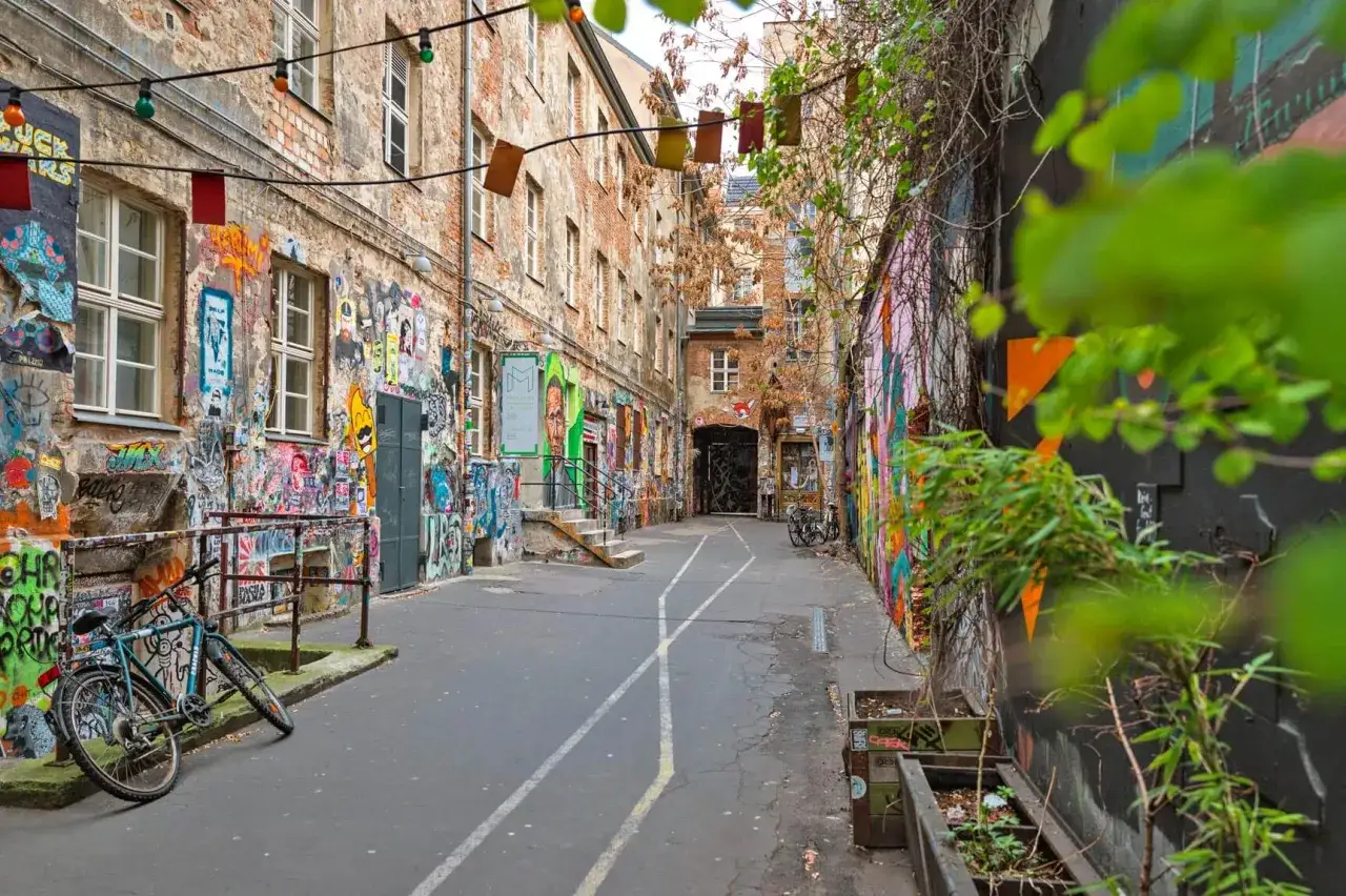 Bunte Graffiti-Kunst schm&uuml;ckt eine Gasse in Berlin. Ein Fahrrad lehnt an einer Wand. Entdecke diese und weitere Berlin Insider Tipps!