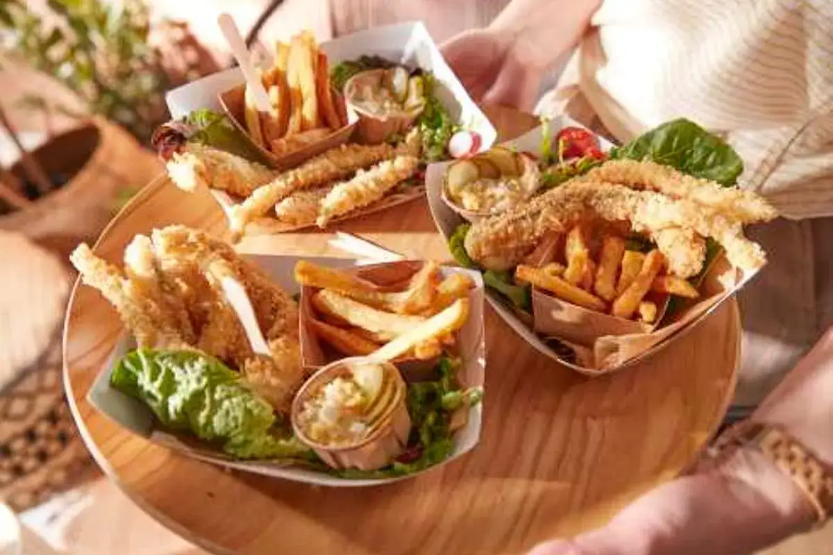 Trois portions de poisson pan&eacute; et frites, servies avec une salade et une sauce tartare cr&eacute;meuse.