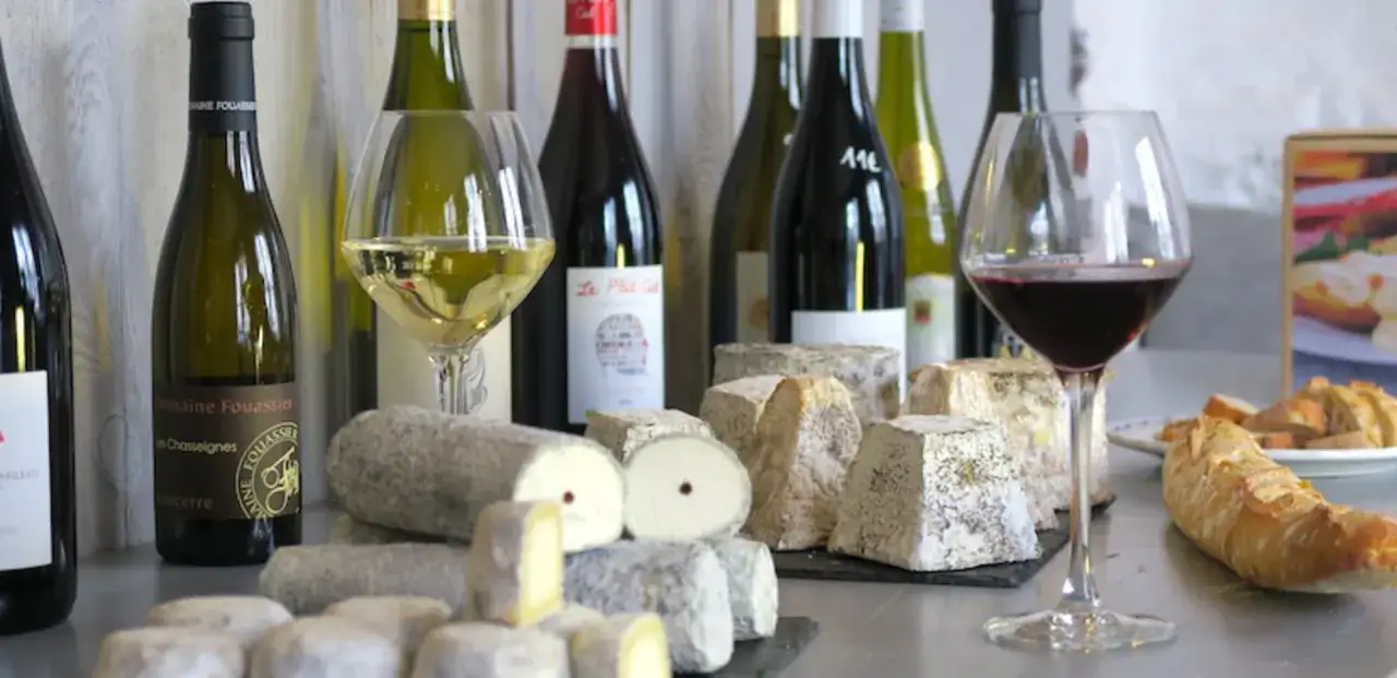Dégustation de vins et de fromage de chèvre du Pays de la Loire, avec des bouteilles et des verres de vin, et une sélection de fromages affinés.