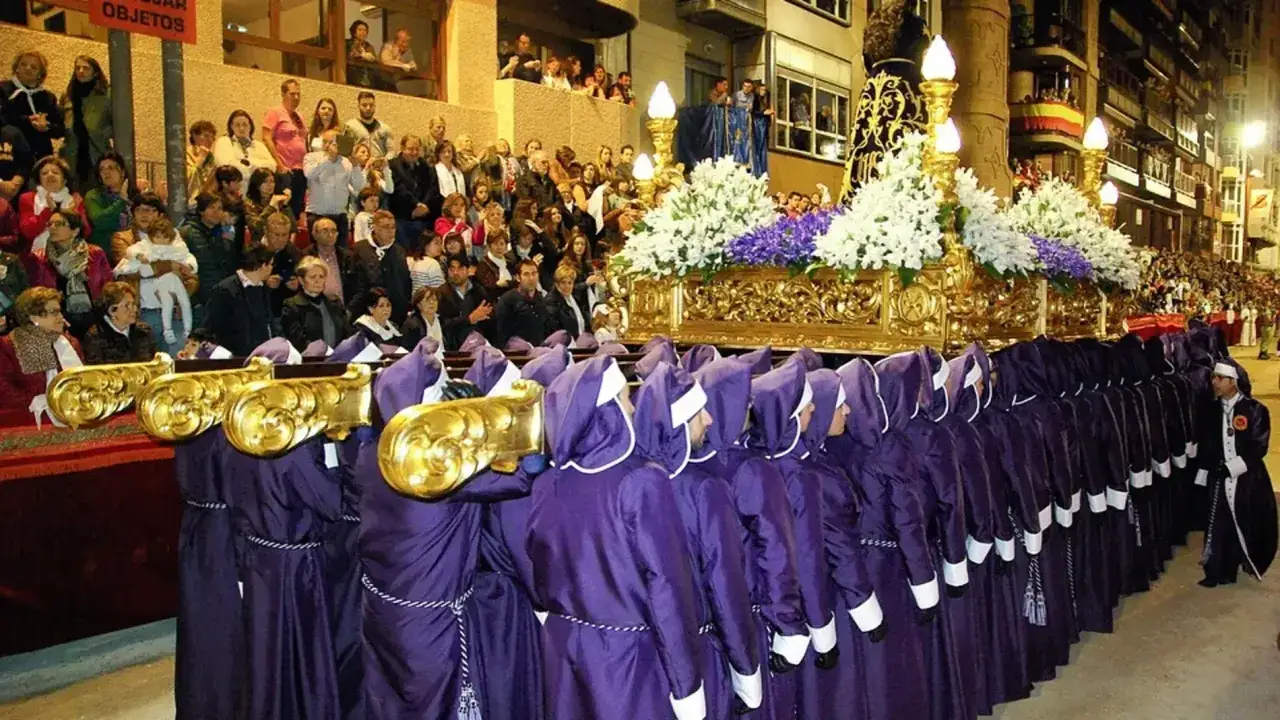 Procesi&oacute;n de Semana Santa con paso dorado y nazarenos morados. Un evento para considerar donde viajar en Semana Santa.