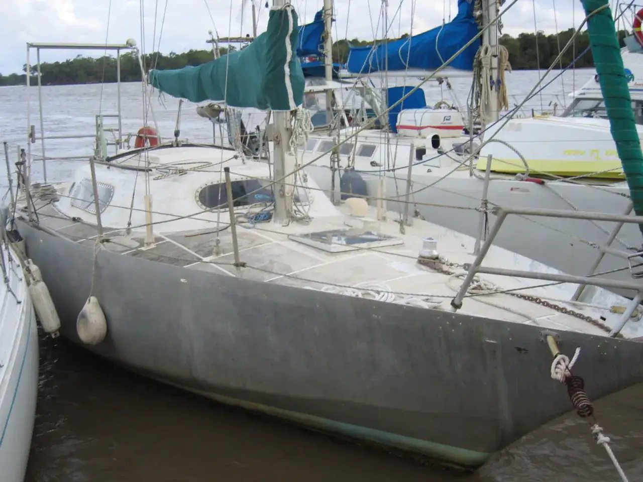 Voilier gris amarré, prêt pour une brise de mer 31. Voiles vertes et bleues, cordages et pare-battages.