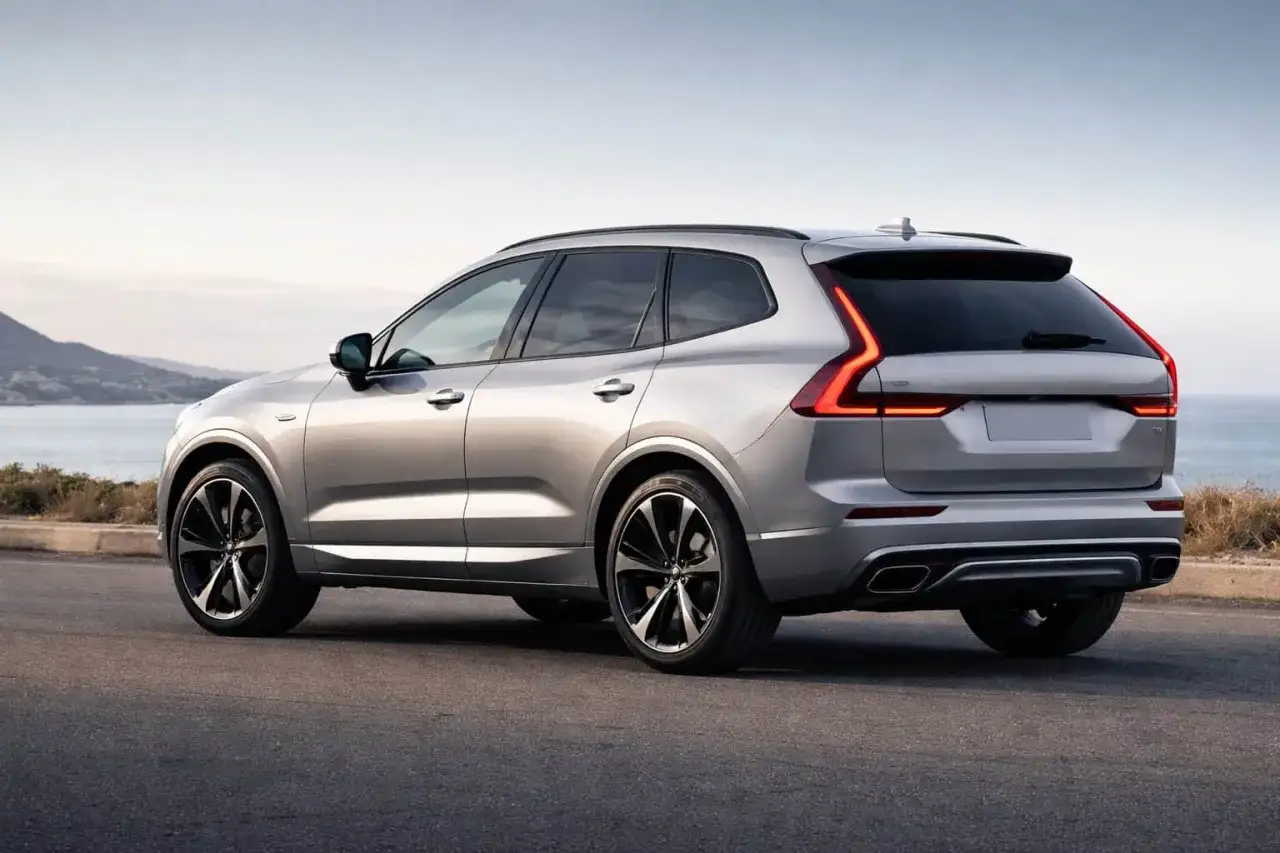 Silver Volvo XC60 laddhybrid testad l&auml;ngs en kustv&auml;g. Vackert landskap med hav och berg i bakgrunden.