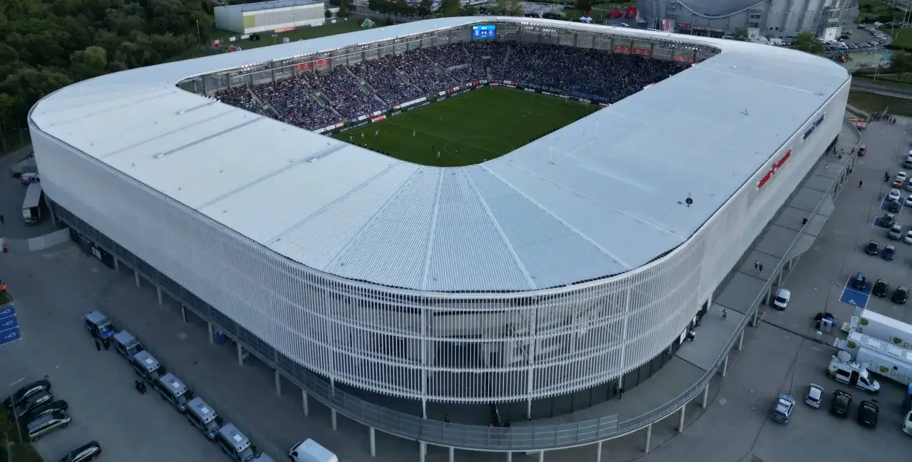 Widok z lotu ptaka na stadion podczas meczu w Płocku. Tłumy kibic&oacute;w na trybunach, zielona murawa i nowoczesna architektura obiektu.
