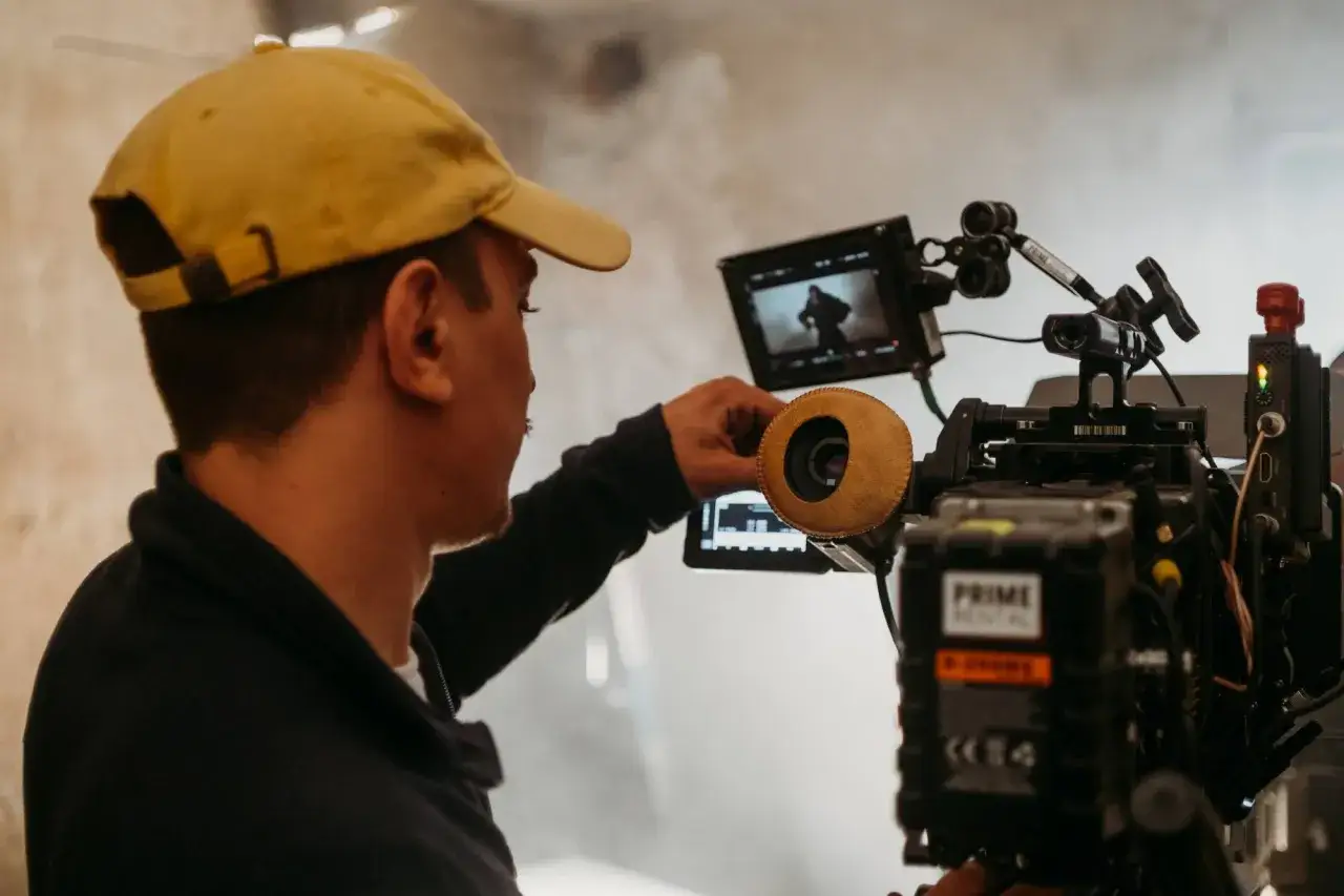 Operador ajusta la cámara profesional, capturando tomas de b-roll para un proyecto cinematográfico.