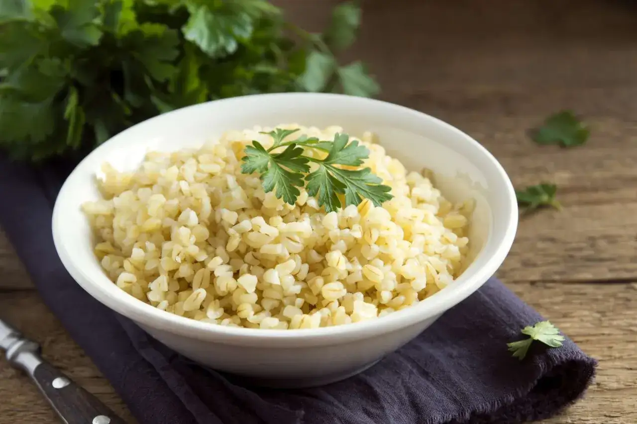Sch&uuml;ssel mit gekochtem Bulgur, garniert mit Petersilie. Eine gesunde Mahlzeit, reich an Bulgur Protein.