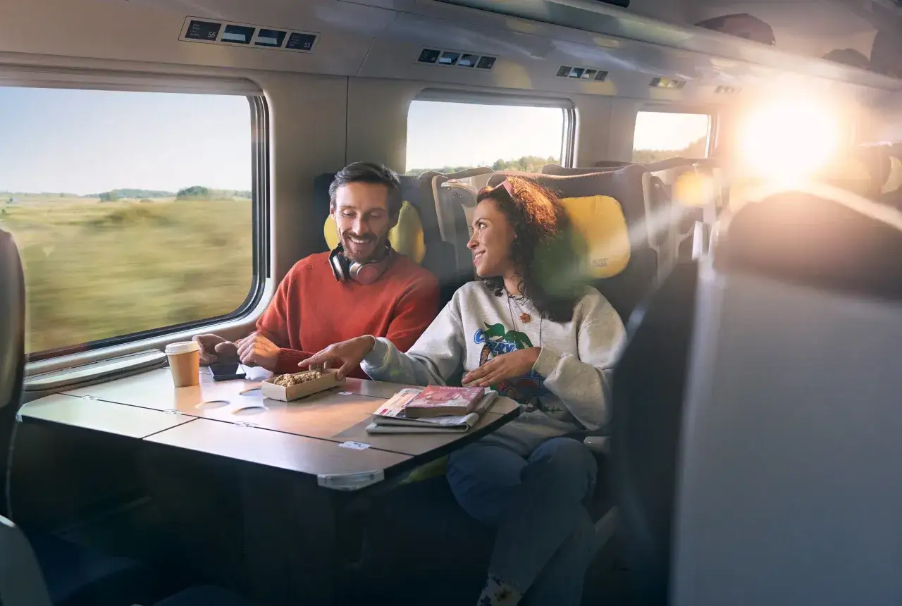 Para podróżuje pociągiem, ciesząc się podróżą i **intercity wifi**.