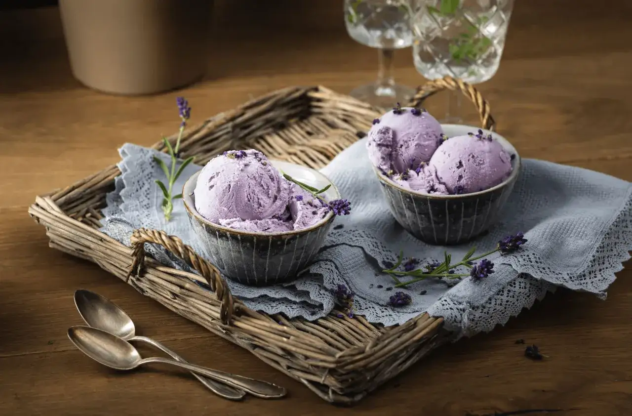 Zwei Schalen mit cremigem Lavendeleis, garniert mit Lavendelblüten. Ein köstliches Lavendeleis Rezept zum Nachmachen.