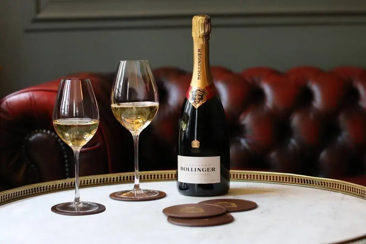 Bouteille de champagne Bollinger Special Cuvée et deux verres remplis, sur un plateau en marbre. Un avis sur ce champagne Bollinger est à venir.