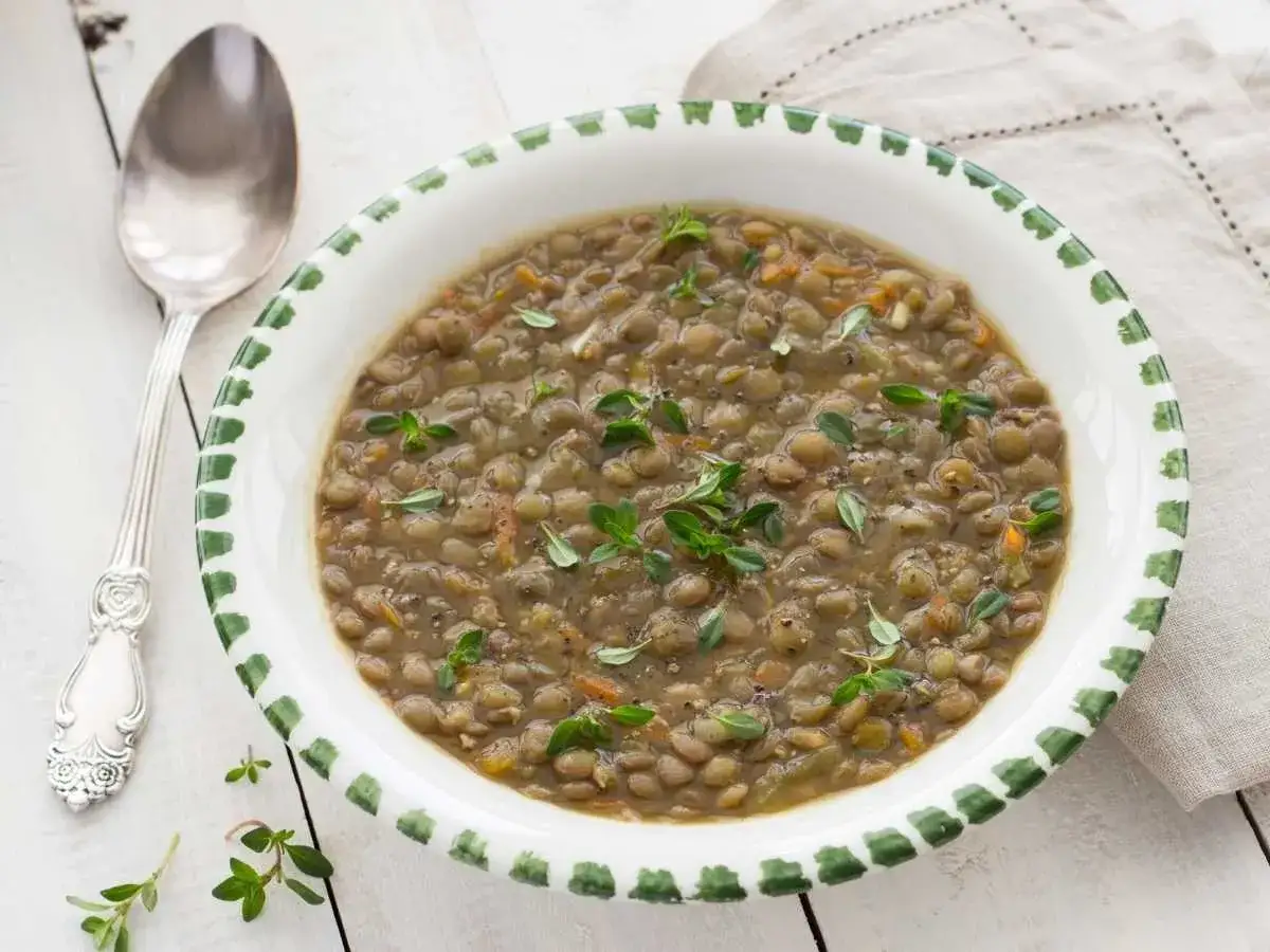 Un plato de lentejas guisadas, perfectas para la olla express, adornado con tomillo fresco.