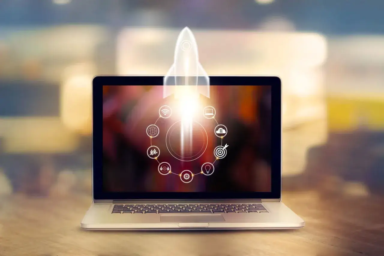 Laptop z rakietą startującą z ekranu, symbolizującą jak przyspieszyć laptopa. Ikony wokół rakiety sugerują optymalizację.
