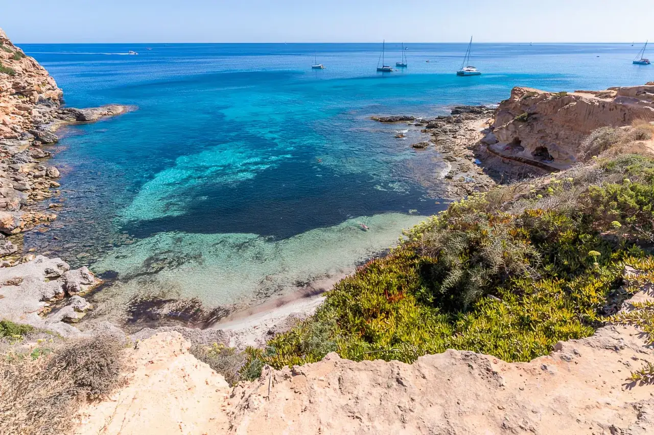 Calas de aguas turquesas y arena dorada, veleros navegando. Un día perfecto para descubrir qué ver en Formentera.