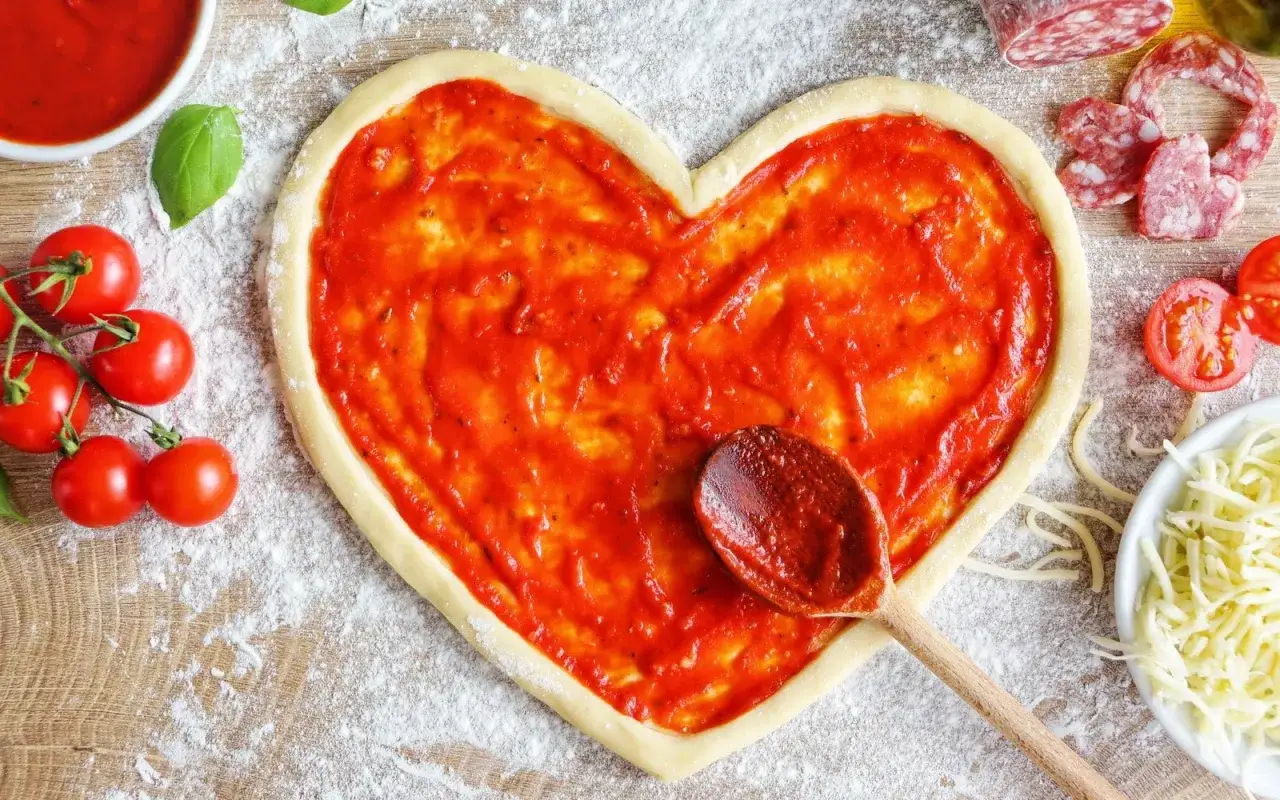 Herzförmiger Pizzateig mit bester Tomatensauce, frischen Tomaten und Basilikum.