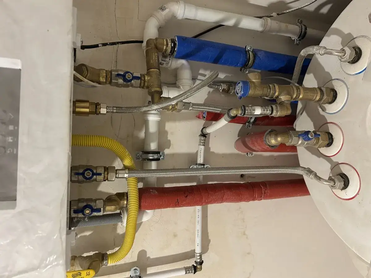 System hydrauliczny z piecem gazowym, widoczne rury, zawory i przewody. Kondensat z pieca gazowego odprowadzany jest przez żółty wąż.
