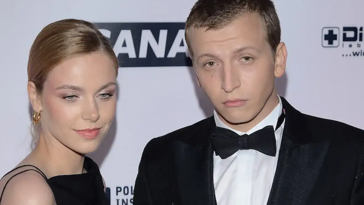 Maciej Musiałowski z partnerką na ściance. Elegancki garnitur i sukienka podkreślają ich styl.