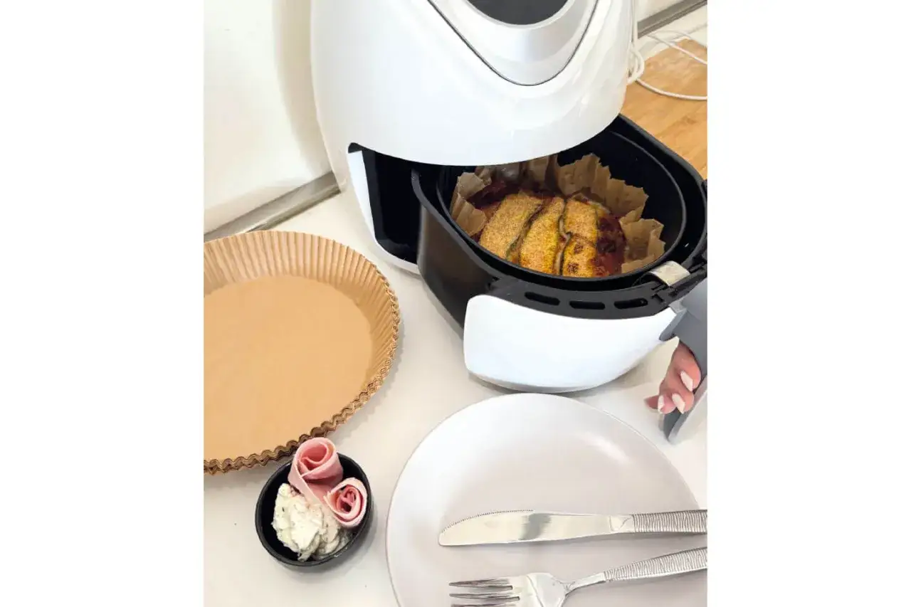 Muffin preparati nella friggitrice ad aria, pronti per essere gustati. Accanto, una teglia di carta e un piattino con formaggio e salumi.