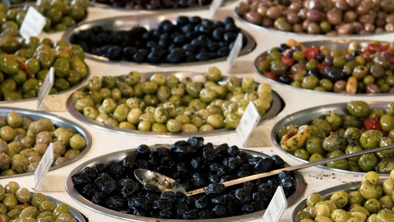 Variedad de aceitunas en bandejas: verdes, negras, y ali&ntilde;adas, incluyendo empeltre o arbequina.
