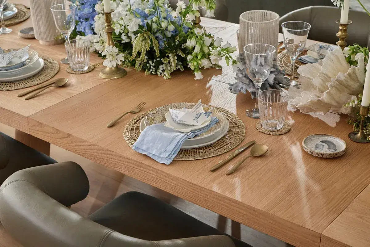 A beautifully set wooden dining table with floral arrangements and place settings. This scene offers inspiration for how to choose dining chairs that complement a refined table setting.