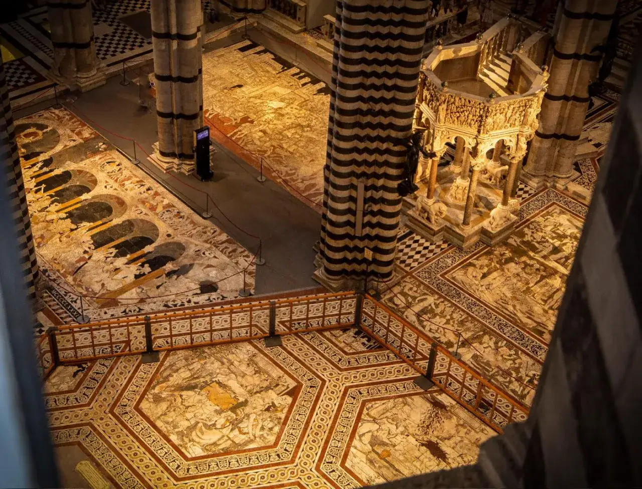 Il magnifico pavimento del Duomo di Siena, un capolavoro di tarsia marmorea, svela scene bibliche e mitologiche.
