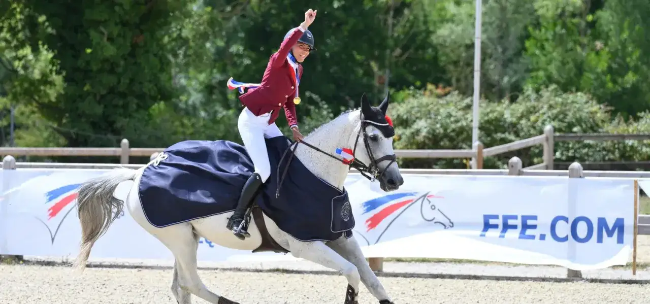Cavalière victorieuse, médaille d'or autour du cou, célèbre sa victoire avec son cheval. Un beau jour pour le salaire cavalier pro !