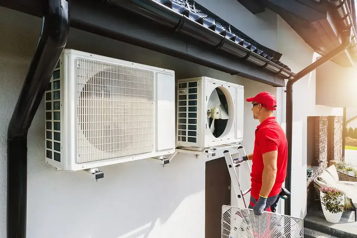 Instalator montuje bezawaryjne pompy ciepła na ścianie domu.