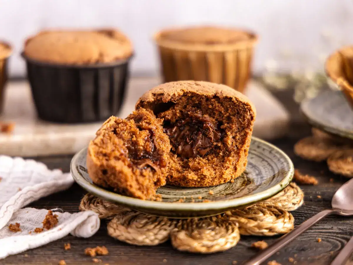 Saftige Nutella Muffins, einer aufgeschnitten, zeigt eine köstliche Füllung. Mehr Muffins im Hintergrund.