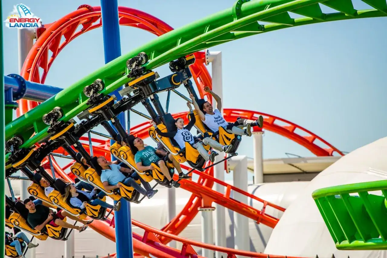 Ludzie krzyczą z radości na żółtej kolejce górskiej rmf dragon roller coaster w Energylandii.