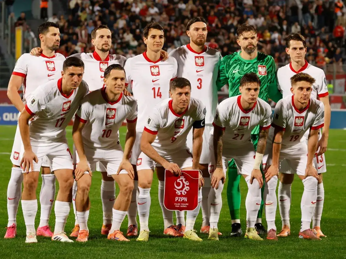 Piłkarze reprezentacji Polski w białych strojach, gotowi do gry. To efekt powołań do kadry, która walczy o zwycięstwo.