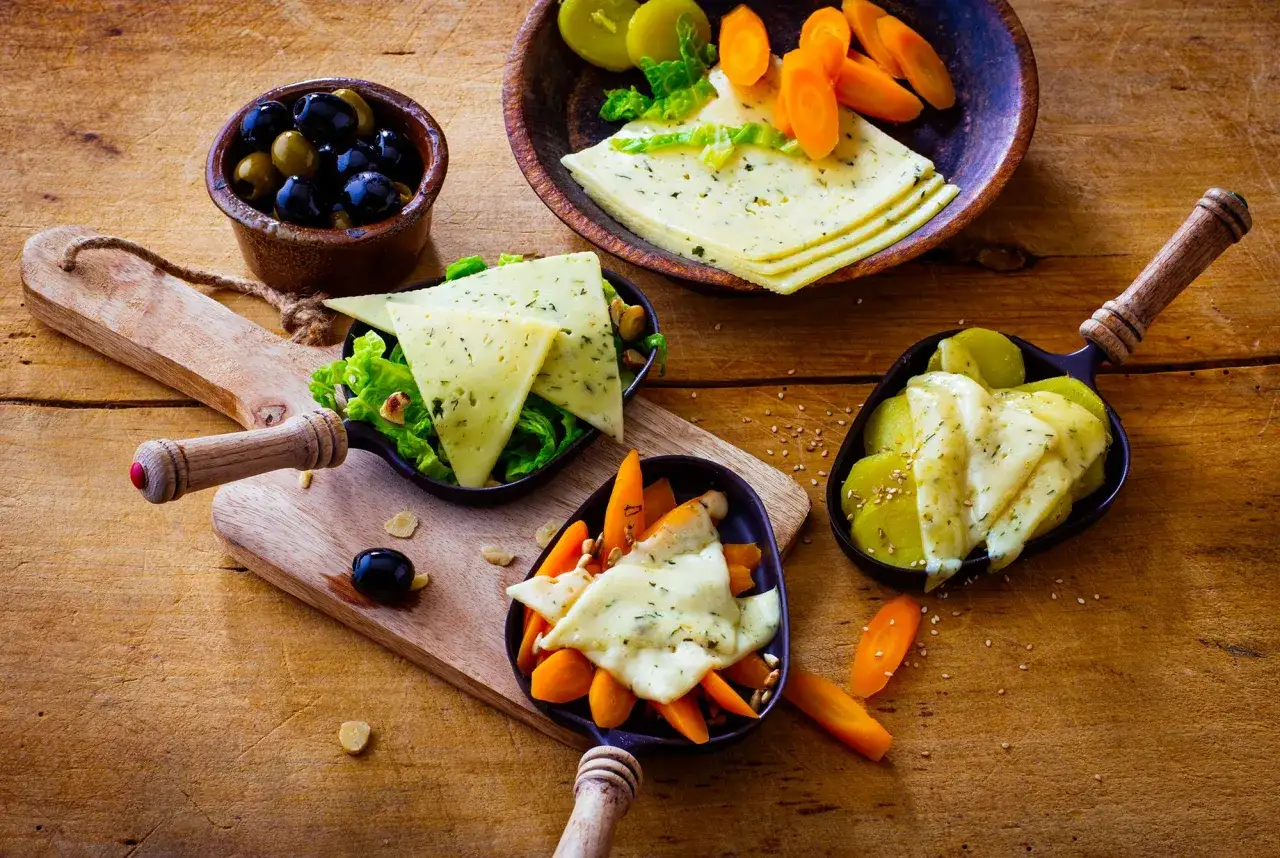 Raclette végétarienne : fromage fondu sur des légumes croquants, olives noires et vertes, carottes et pommes de terre. Un délice !