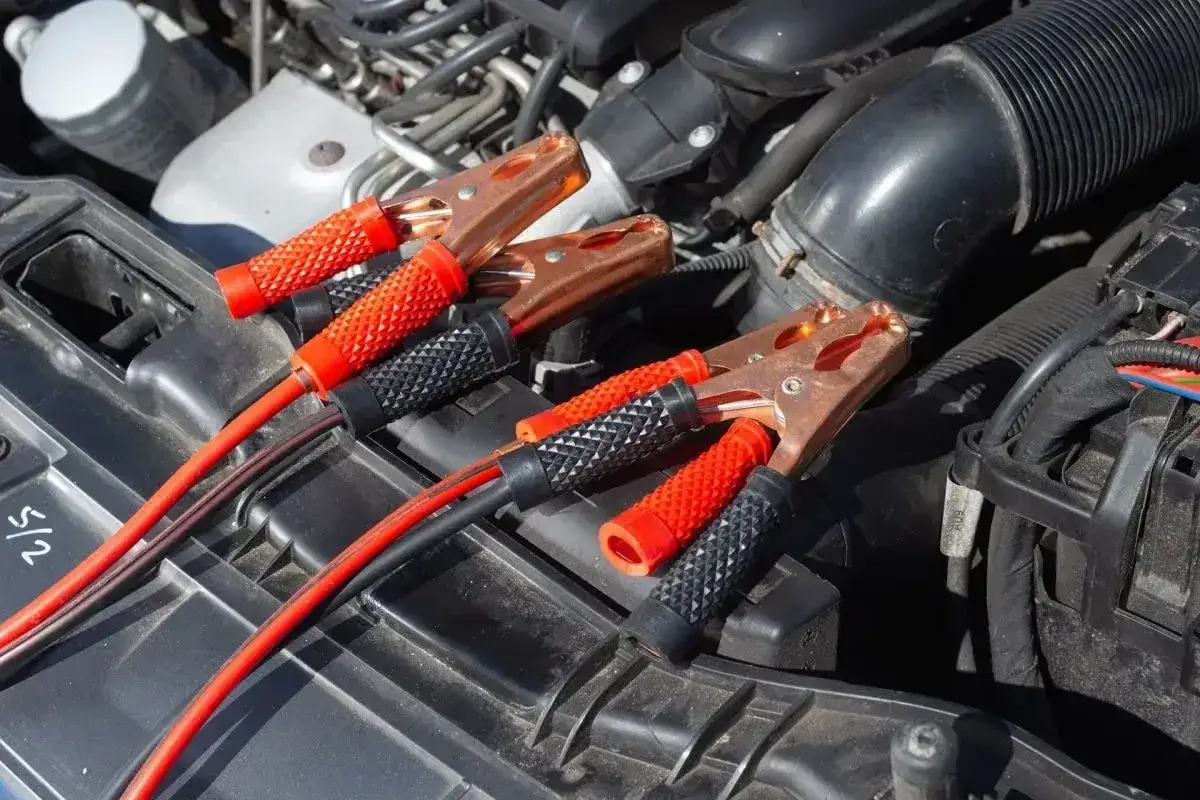 Kable rozruchowe podłączone do silnika. Auto nie odpala, akumulator sprawny, próba uruchomienia.