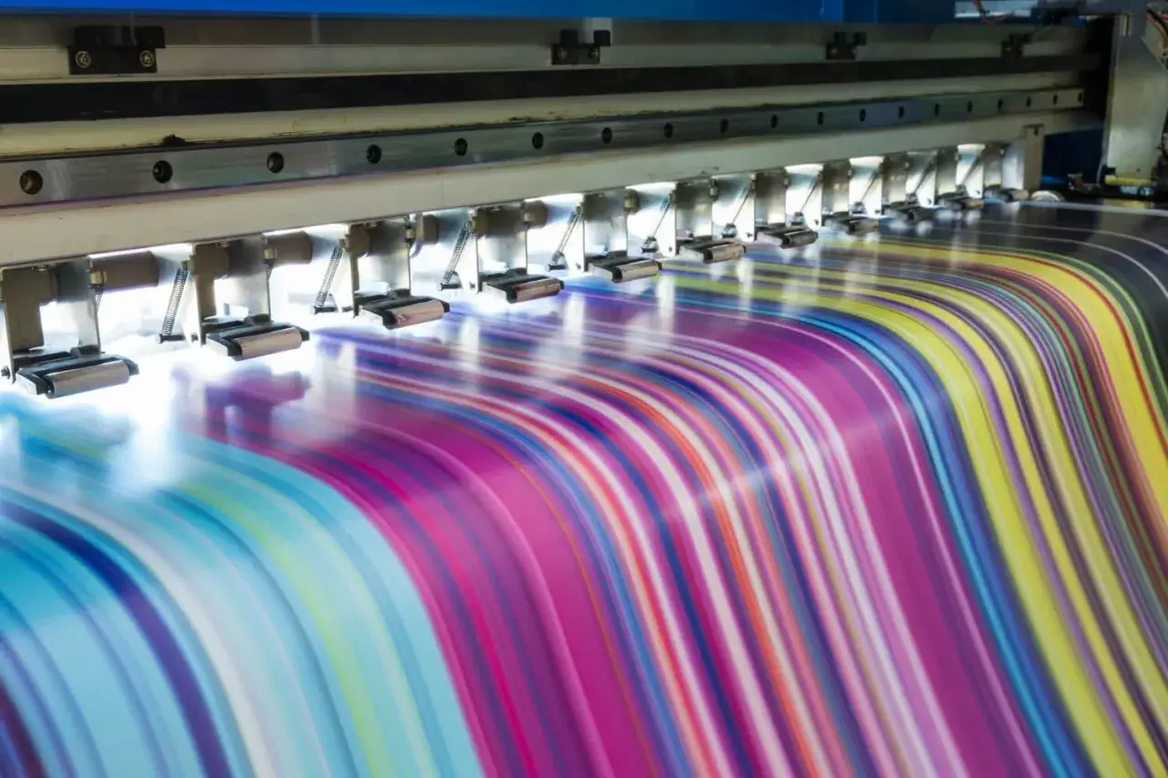 M&aacute;quina de impresi&oacute;n industrial creando un patr&oacute;n de rayas de colores vibrantes. Las ventajas de la imprenta se hacen evidentes en la velocidad y calidad de esta producci&oacute;n.