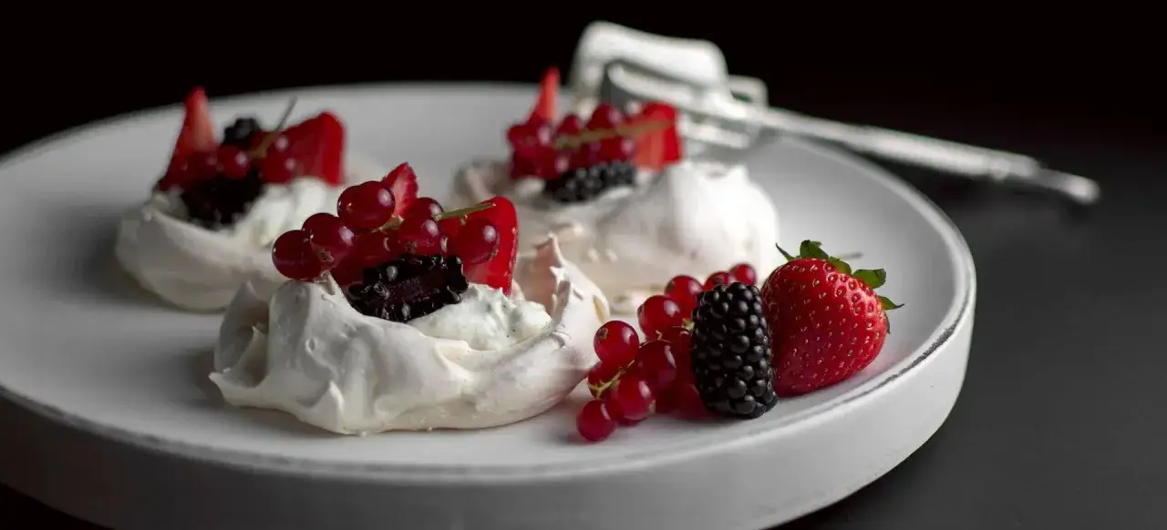 Pavlova-Rezept: zarte Baiser-T&ouml;rtchen mit Sahne und frischen Beeren wie Erdbeeren, Johannisbeeren und Brombeeren.