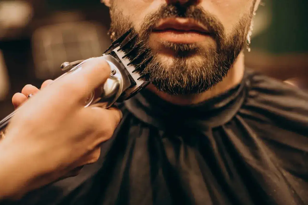 Un hombre decide dejar crecer la barba, mientras un barbero usa una recortadora para darle forma.