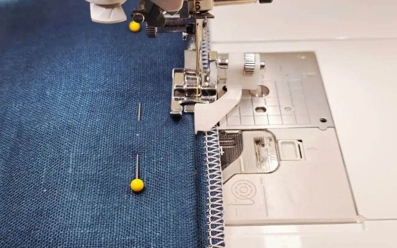 Sewing a hem with a blind hem foot. The foot guides the fabric for a nearly invisible stitch.