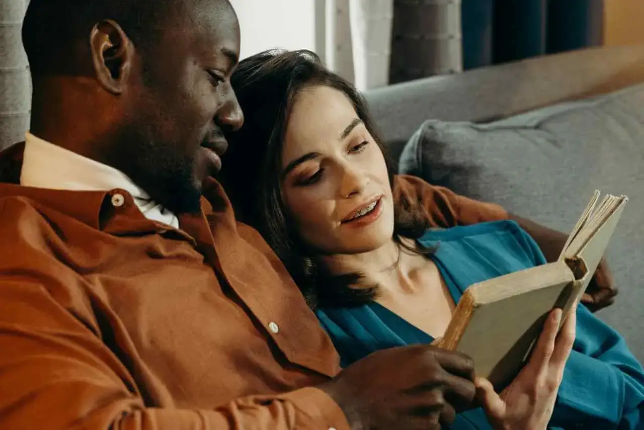 Een stel leest samen een boek, genietend van elkaars gezelschap. Ze vermijden de valkuilen van een lat relatie door tijd samen te investeren.