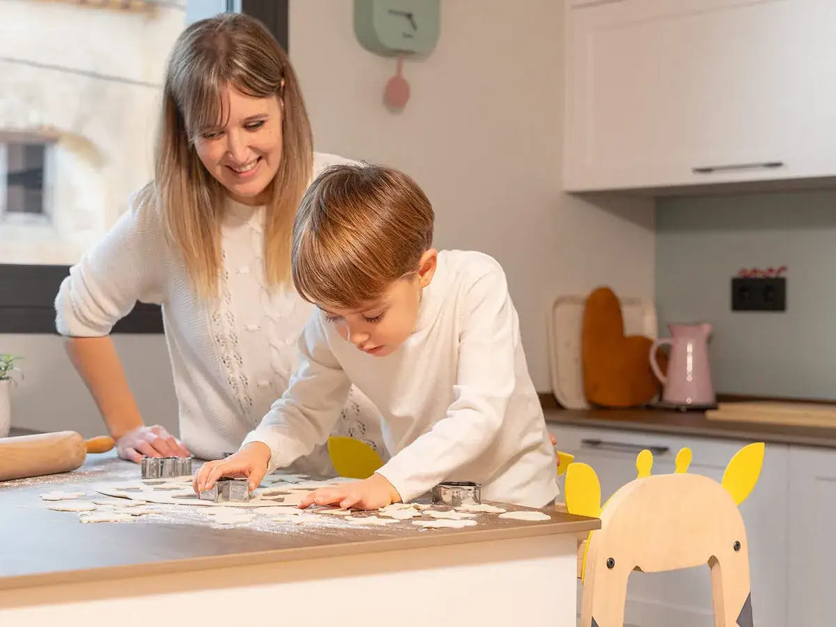 Madre e hijo cortan galletas en la cocina. Una actividad divertida de invierno para niños, creando dulces caseros.