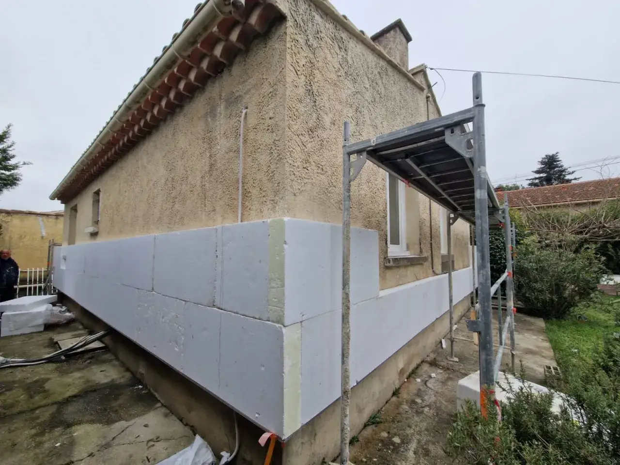 Maison en cours d'isolation thermique écologique avec des panneaux blancs. Échafaudage sur le côté.