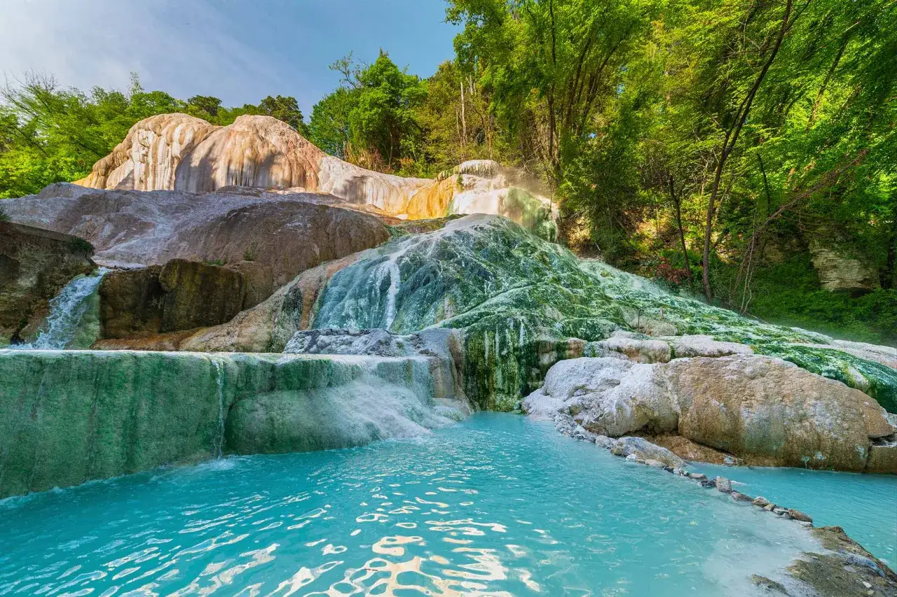 T&uuml;rkisblaue Becken und terrassierte Wasserf&auml;lle, die von mineralischen Ablagerungen &uuml;berzogen sind, bilden eine nat&uuml;rliche Oase. Die **Schwefelquellen Toskana** sprudeln hier inmitten &uuml;ppiger Vegetation.