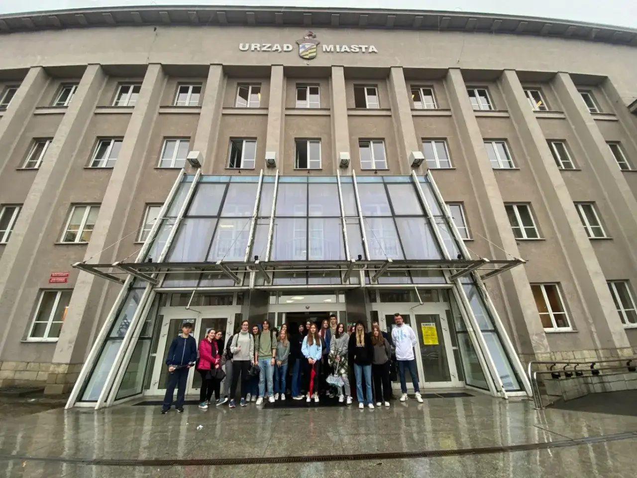 Grupa młodzieży przed Urzędem Miasta w Sosnowcu, gdzie znajduje się biuro paszportowe.