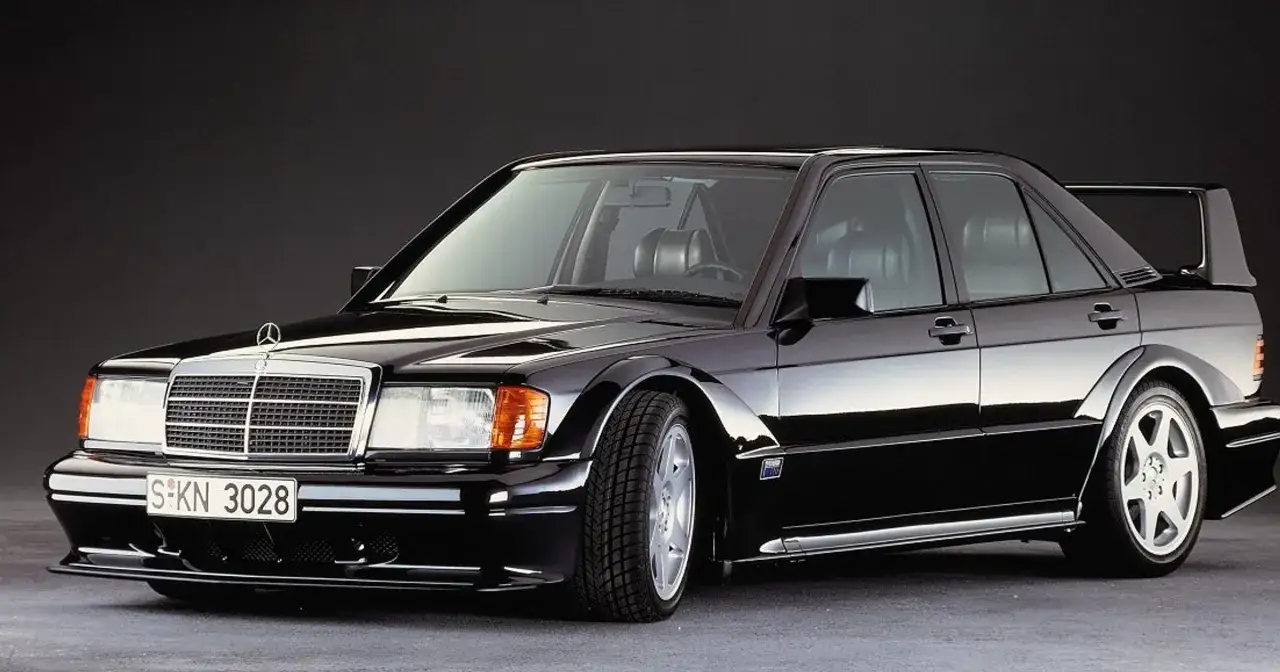 Czarny Mercedes-Benz 190 (W201) z charakterystycznym spoilerem i szerokimi błotnikami, gotowy do podboju dróg.