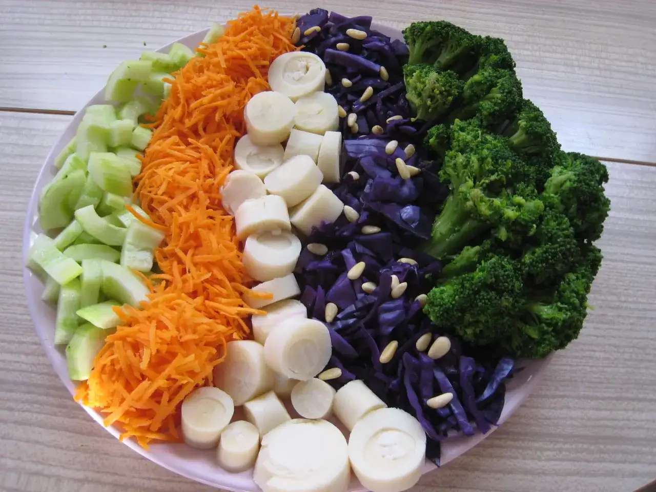 Une salade compos&eacute;e color&eacute;e avec des concombres, carottes r&acirc;p&eacute;es, c&oelig;urs de palmier, chou rouge et brocolis.