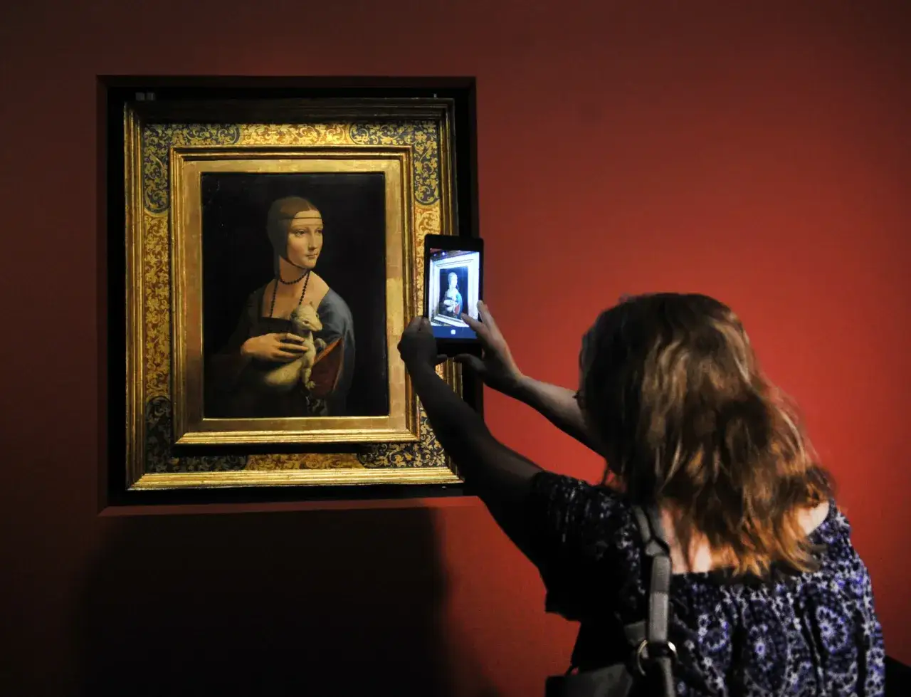 Dama z łasiczką w muzeum, gdzie jest? Kobieta robi zdjęcie słynnego obrazu telefonem.
