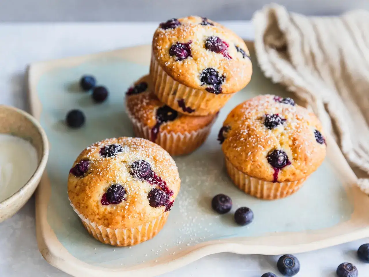 Saftige blaubeermuffins mit Joghurt, bestäubt mit Puderzucker, liegen auf einem Teller.
